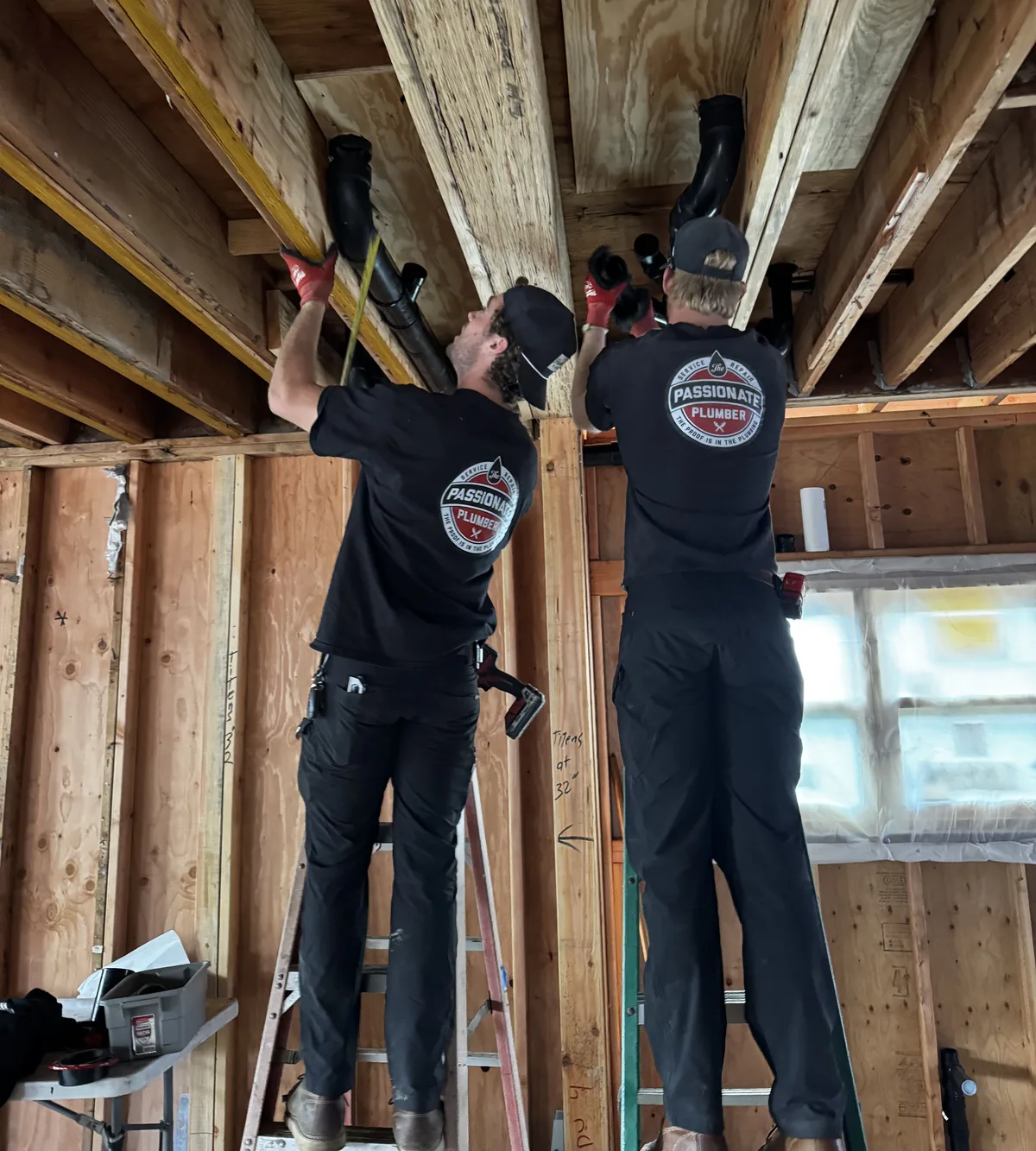 Two Passionate Plumber technicians running new pipe through open ceiling joists