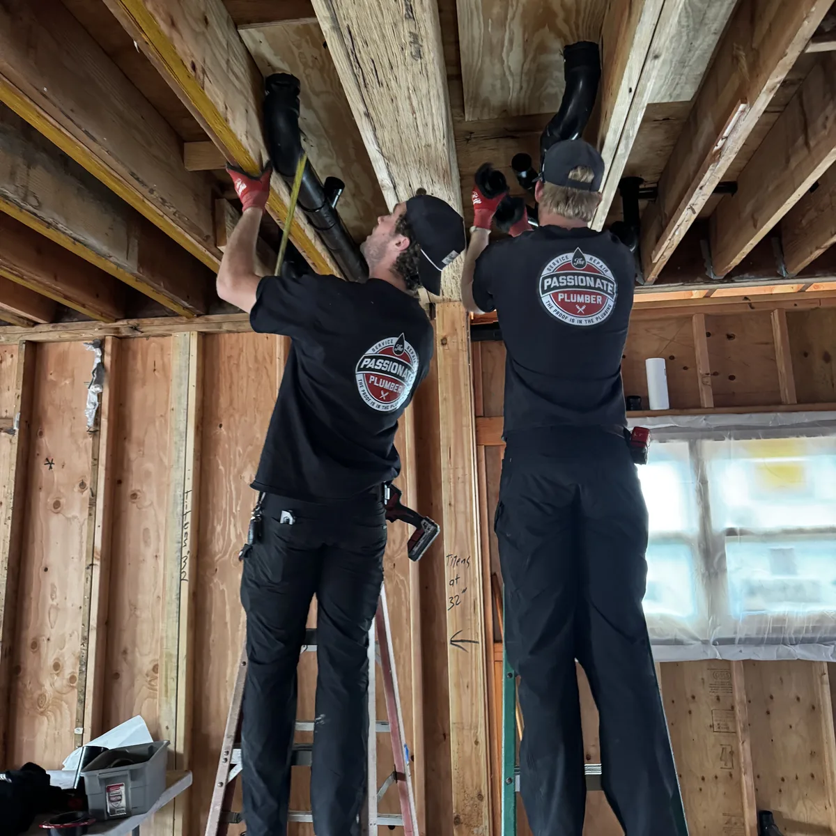 Two Passionate Plumber technicians running new pipe through open ceiling joists