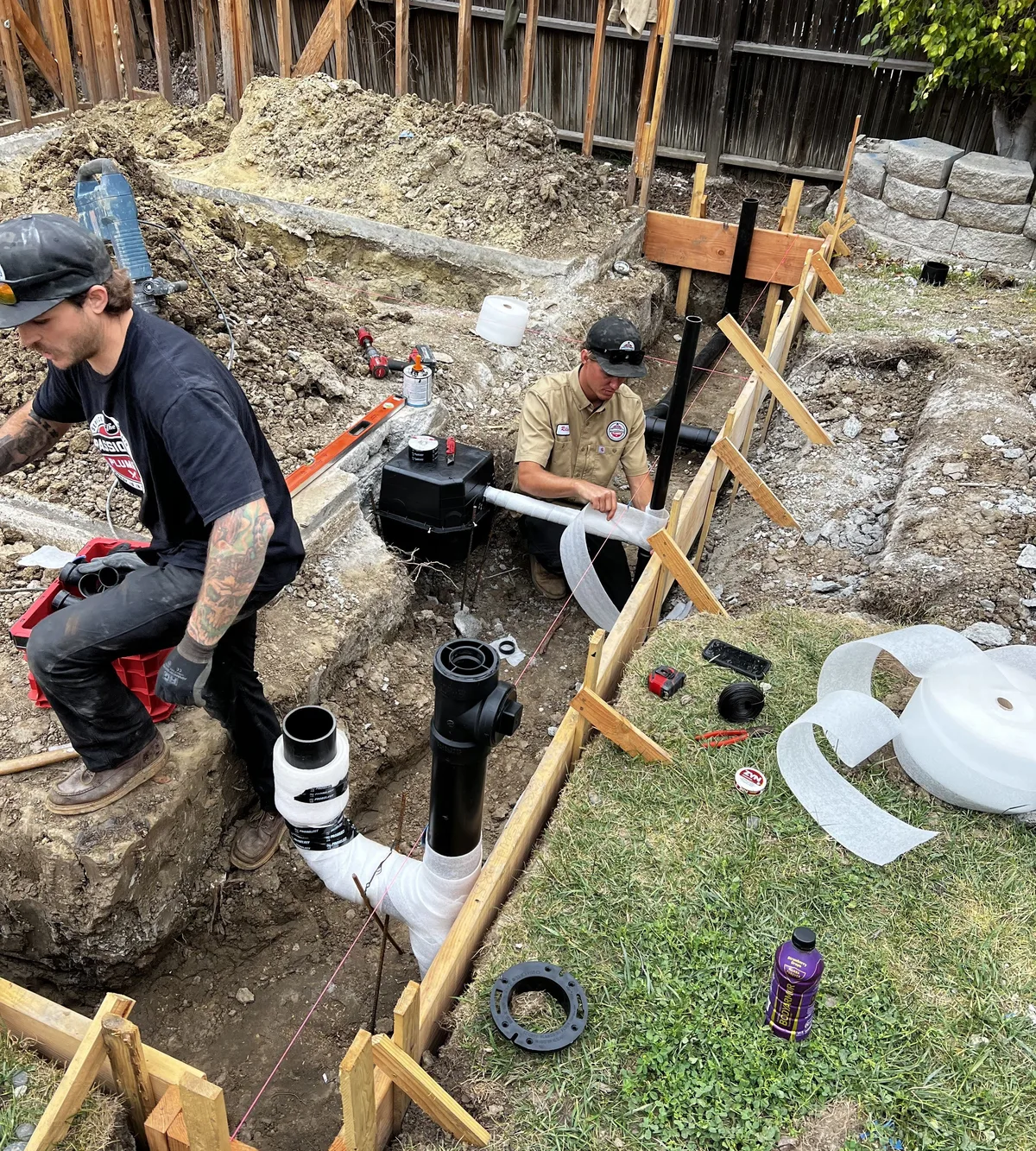 Passionate Plumber technicians replacing a sewer line in an excavated trench