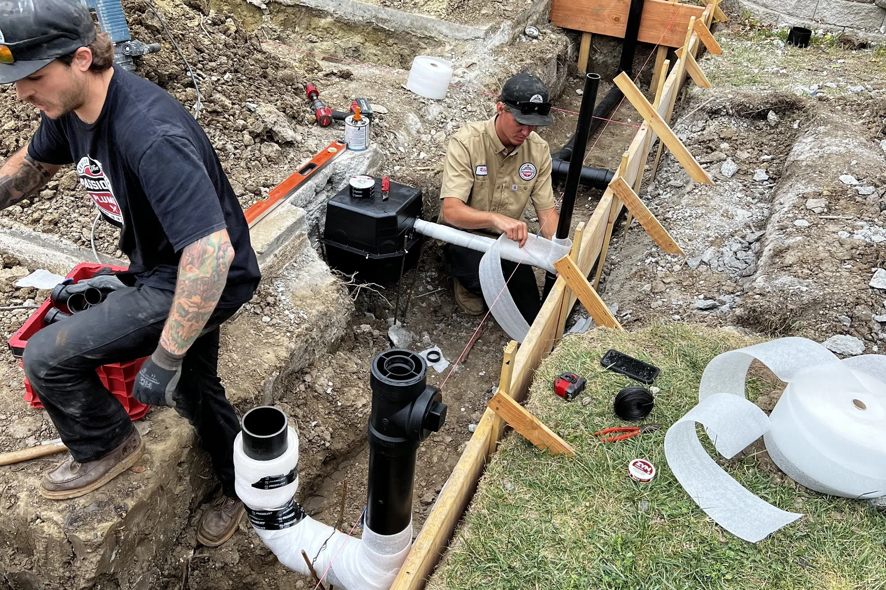 Passionate Plumber technicians replacing a sewer line in an excavated trench